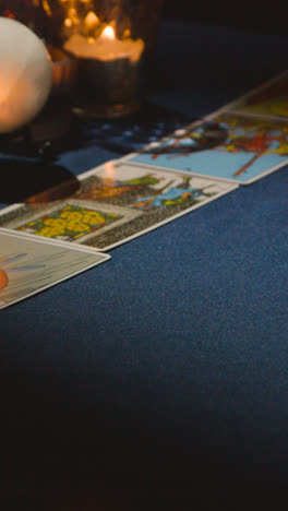 Vertical-Video-Close-Up-Of-Woman-Giving-Tarot-Card-Reading-On-Candlelit-Table-2